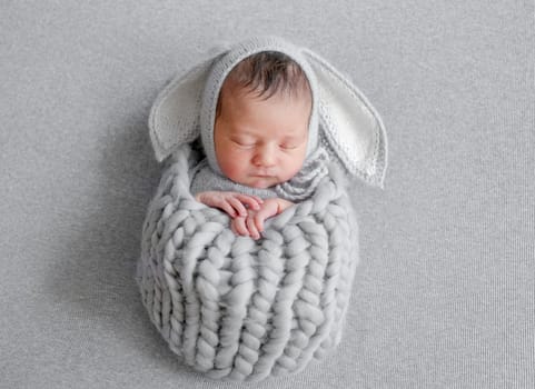 Newborn Girl In Bunny Hat Sleeps During Baby Photo Session In Studio