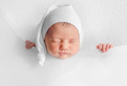 Newborn Girl Sleeps Under Blanket During Infant Photoshoot In Studio