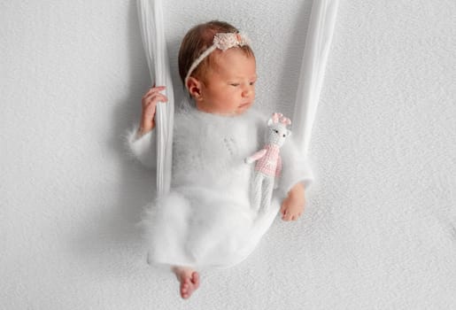 Newborn Girl On Improvised Swing During A Baby Photo Session In Studio