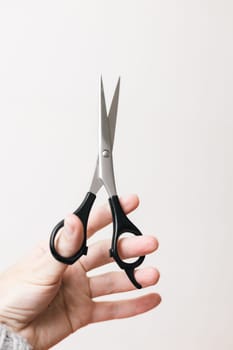 One pair of scissors in the hands of a hairdresser with a black handle on a white background,side view close-up.The concept of tools of a hairdresser,beauty salon,isolate.