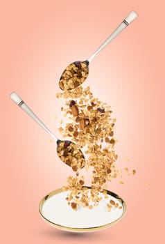 Oatmeal, raisins, cashews and almonds. Granola pours out of a metal spoon