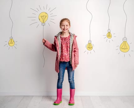 Girl Turns On Painted Wall Light Bulb, Symbolizing Child Invention And Discovery Concept