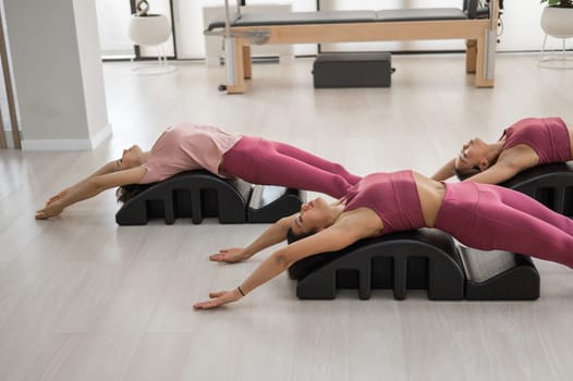 Balanced Body Pilates Arc. Three asian women exercising on pilates arc