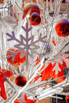 Close-up footage of Christmas Decorations on a Snow-Covered Spruce Tree in dusk, It's snowing, snowflakes are falling, red glass balls and stars, artificial snowflakes, illumination. High quality photo