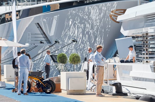 Monaco, Monte Carlo, 28 September 2022 - Invited wealthy clients inspect megayachts at the largest fair exhibition in the world yacht show MYS, port Hercules, yacht brokers, sunny weather. High quality photo