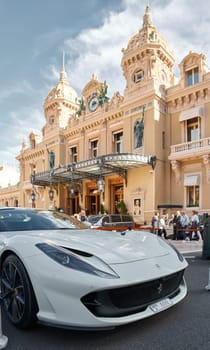 Monaco, Monte-Carlo, 29 September 2022 - Famous square Casino Monte-Carlo at sunny day, Ferrari convertible, luxury cars, wealth life, tourists take pictures of the landmark. High quality photo
