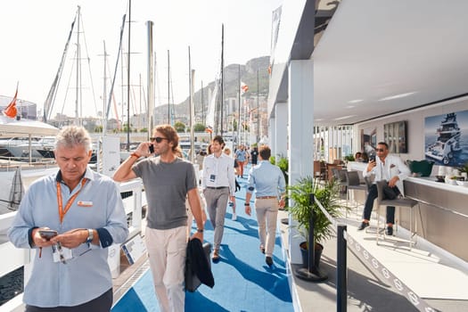 Monaco, Monte Carlo, 29 September 2022 - a handsome stylish man sits on a chair in one of the stands at the mega yacht exhibition, clients and yacht brokers discuss the novelties of boating industry. High quality photo