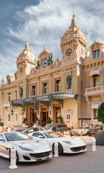 Monaco, Monte-Carlo, 29 September 2022 - Famous square Casino Monte-Carlo at sunny day, Ferrari convertible, luxury cars, wealth life, tourists take pictures of the landmark. High quality photo