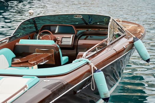 Monaco, Monte Carlo, 29 September 2022 - the wooden side of the luxury motor boat Riva in port of Hercules, sunny glare of the sun, elegance boat, glossy surfaces shine in sunny weather. High quality photo