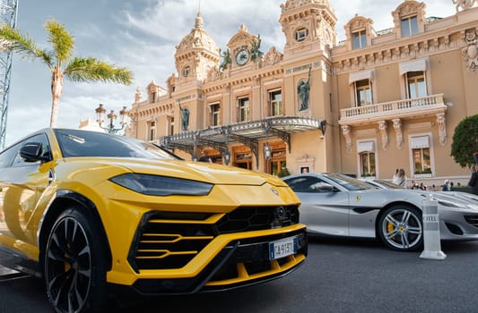 Monaco, Monte-Carlo, 29 September 2022 - Famous square Casino Monte-Carlo at sunny day, yellow Lamborghini SUV, luxury cars, wealth life, tourists take pictures of the landmark. High quality photo