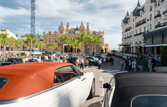 Monaco, Monte-Carlo, 29 September 2022 - Square Casino Monte-Carlo at sunny day, luxury cars, famous Hotel de Paris, wealth life, tourists take pictures of the landmark, pine trees, flowers. High quality photo