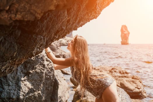 Woman travel sea. Young Happy woman in a long red dress posing on a beach near the sea on background of volcanic rocks, like in Iceland, sharing travel adventure journey