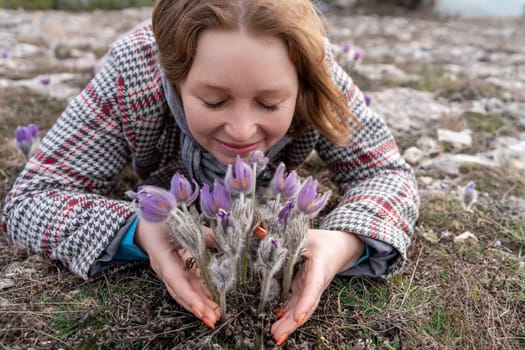 Dream grass woman spring flower. Woman lies on the ground and hugs flowers pasqueflower or Pulsatilla Grandis flowers.