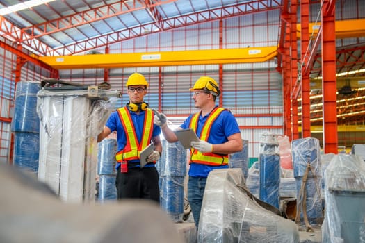 Front view of two factory workers or technician hold tablet check and maintenance the machine in factory workplace.