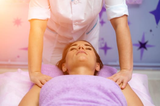 Relaxing massage. European woman getting facial massage in spa salon, side view.