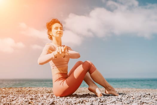 Young woman with long hair in white swimsuit and boho style braclets practicing outdoors on yoga mat by the sea on a sunset. Women's yoga fitness routine. Healthy lifestyle, harmony and meditation