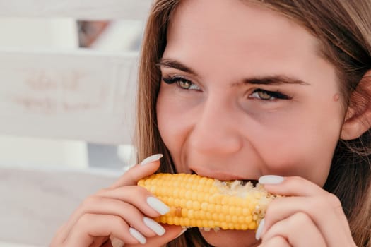 Healthy vegetarian hipster woman in summer outfit eat grilled corn and look to camera. Sexy lady on sea beach sunset or ocean sunrise. Travel, explore, active yoga and meditation lifestyle concept.