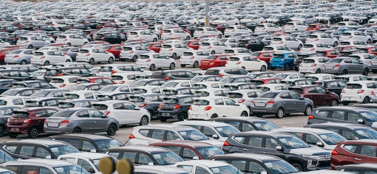 Lamchabang, Thailand - July 02, 2023 In a distribution center at a sunny car factory, new cars are neatly lined up. The top view offers a glimpse of the bustling parkinga hub of global industry.