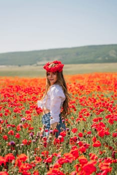 Happy woman in a poppy field in a white shirt and denim skirt with a wreath of poppies on her head posing and enjoying the poppy field