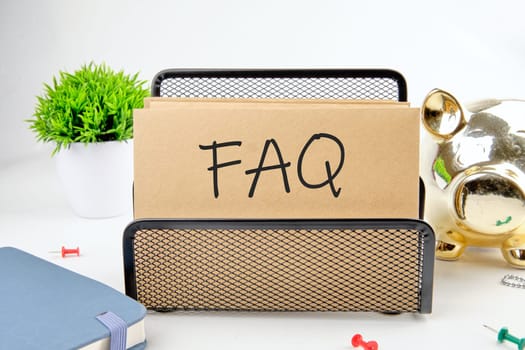 FAQ text on paper next to piggy bank, notepad, flower on a white background