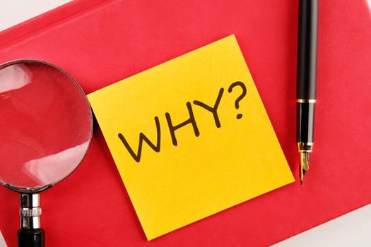 WHY the inscription on the sticker lying on a red notebook next to a magnifying glass and a fountain pen