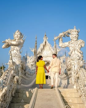 White Temple Chiang Rai Thailand,a diverse couple of men and women visit Wat Rong Khun temple, Northern Thailand at sunset