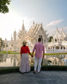 White Temple Chiang Rai Thailand,a diverse couple of men and women visit Wat Rong Khun temple, Northern Thailand at sunset