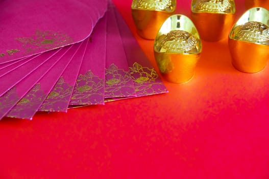Red envelope and golden ingots on red cover background with Chinese New Year wishes