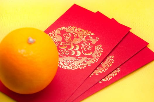 Chinese New Year red packets and orange on yellow cover background. Chinese festive season concept.
