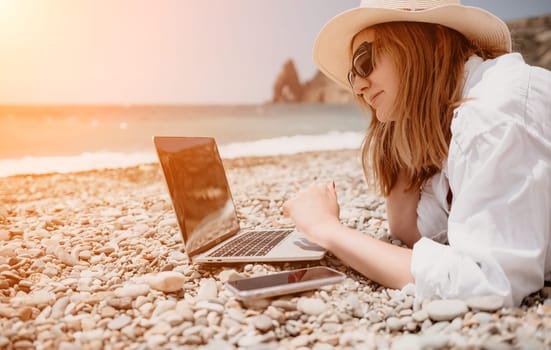 Woman sea laptop. Business woman in yellow hat working on laptop by sea. Close up on hands of pretty lady typing on computer outdoors summer day. Freelance, digital nomad, travel and holidays concept