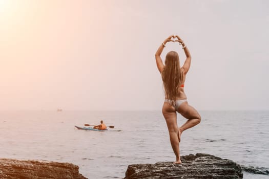 Woman meditating in yoga pose silhouette at the ocean, beach and rock mountains. Motivation and inspirational fit and exercising. Healthy lifestyle outdoors in nature, fitness concept.