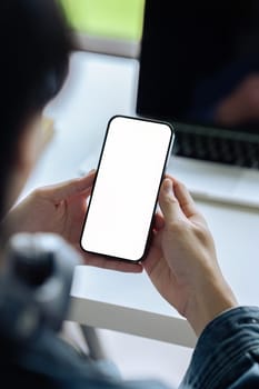 Mockup image of a man holding and using mobile phone with blank desktop screen.