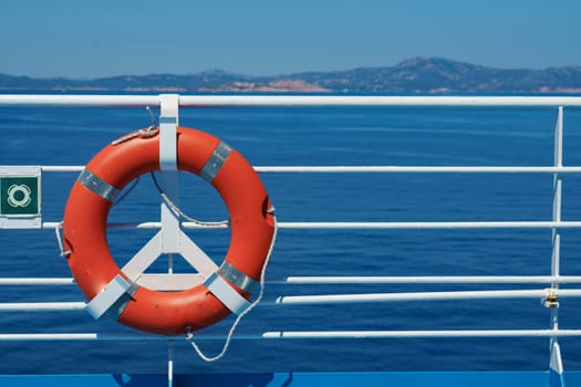 a red lifebuoy hangs on board a ferry cruise ship against the backdrop of a blue sea and a cloudless sky. High quality photo
