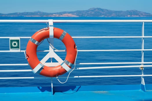 a red lifebuoy hangs on board a ferry cruise ship against the backdrop of a blue sea and a cloudless sky. High quality photo