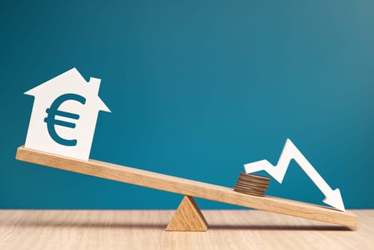 Reducing the interest rate on mortgages in the Europe. Reducing the cost of a loan for real estate or rental housing. Model of a house with a Euro symbol on the scales. High quality photo