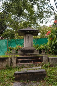 Singapore - July 9 2023: Japanese Tombstone Amid Red Flora