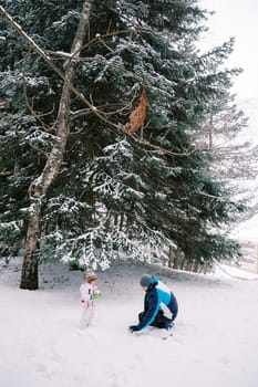 Little girl and dad making snowballs in a snowy forest. High quality photo
