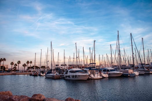 Sailboat harbor in the port evening photo. Beautiful moored sail yachts in the sea, modern water transport Barcelona, Catalonia. Bright sunset and dusk. High quality picture for wallpaper, article