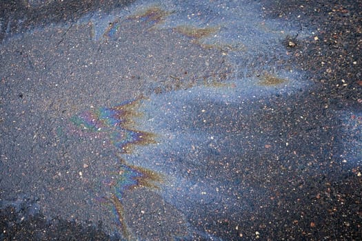 Fuel stain on wet asphalt. Colored stains from a gasoline leak on the road.