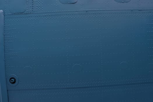 Riveted metal from an aircraft. Aircraft skin close up. Detail of an old grunge blue metal plate piece with bolts, aluminum surface background.