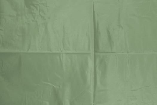 Abstract background of shiny slightly wrinkled fabric. Green texture for copy space design.