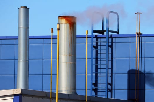 Chimney with smoke, stairs, wall, building facade in blue.