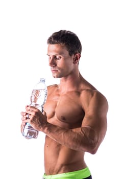 Handsome muscular young man shirtless, drinking water from bottle, isolated on white