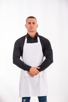 Attractive chef or waiter posing, wearing white apron and black shirt isolated on white background, in studio shot