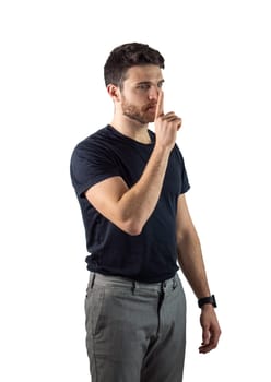 Hush. Young handsome man silencing you, saying shut up, isolated on white in studio shot. Young man doing hush sign with finger over his mouth, looking at camera, isolated on white, silencing
