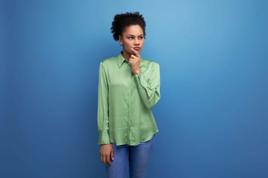 young hispanic brunette lady dressed in a green stylish shirt against the background with copy space.