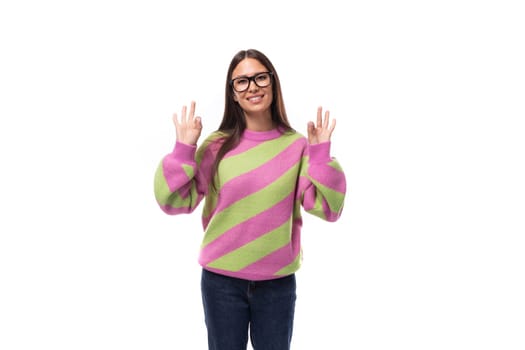 portrait of a smart young brunette woman in a casual stylish pink-green sweater on a white background with copy space.
