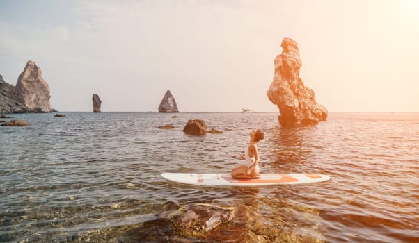 Woman sup yoga. Middle age sporty woman practising yoga pilates on paddle sup surfboard. Female stretching doing workout on sea water. Modern individual hipster outdoor summer sport activity