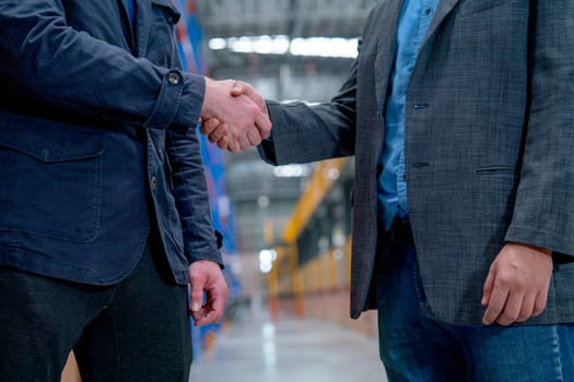 Close up business men shake hands for success of the project in factory industrial workplace.