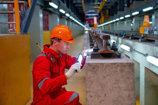 Professional technician worker with safety uniform hold the light tube to work with railroad tracks of electrical or sky train in factory workplace.